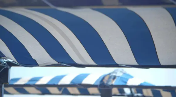 Toldo a rayas azules y blancas, listo para cambiar la tela y proteger del sol.