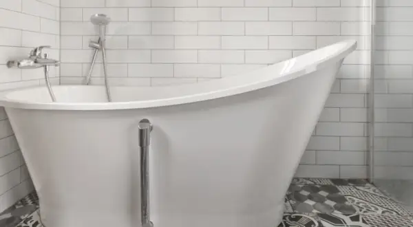Baño moderno con bañera blanca y grifería cromada. El suelo tiene baldosas hidráulicas. Ideal para reparar bañera picada.