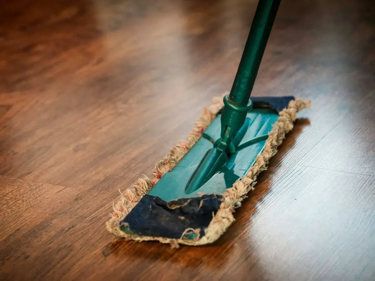 Mopa sobre suelo de madera. Descubre remedios caseros para reparar parquet y mantenerlo como nuevo.