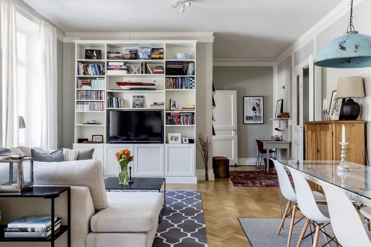 Ideas para cómo distribuir un salón comedor cuadrado: zona de estar con sofá y estanterías, y zona de comedor con mesa de cristal.