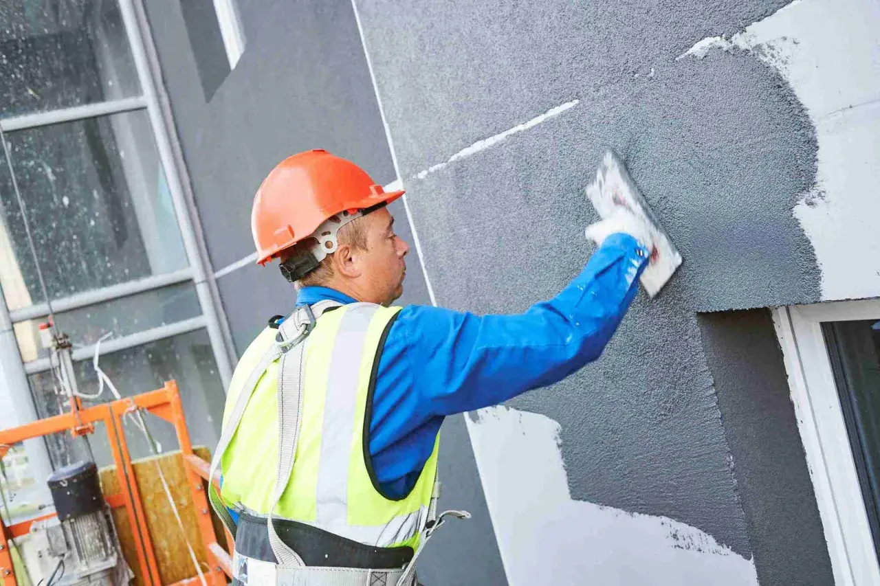 Obrero aplica revestimiento a un panel aislante térmico exterior.