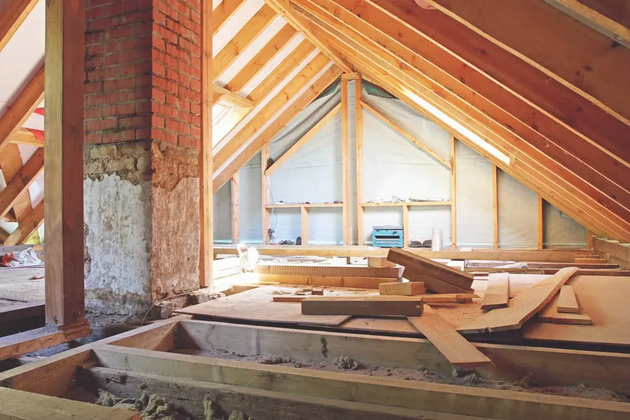 El **altillo de madera** está en construcción, con vigas expuestas y materiales de construcción esparcidos.