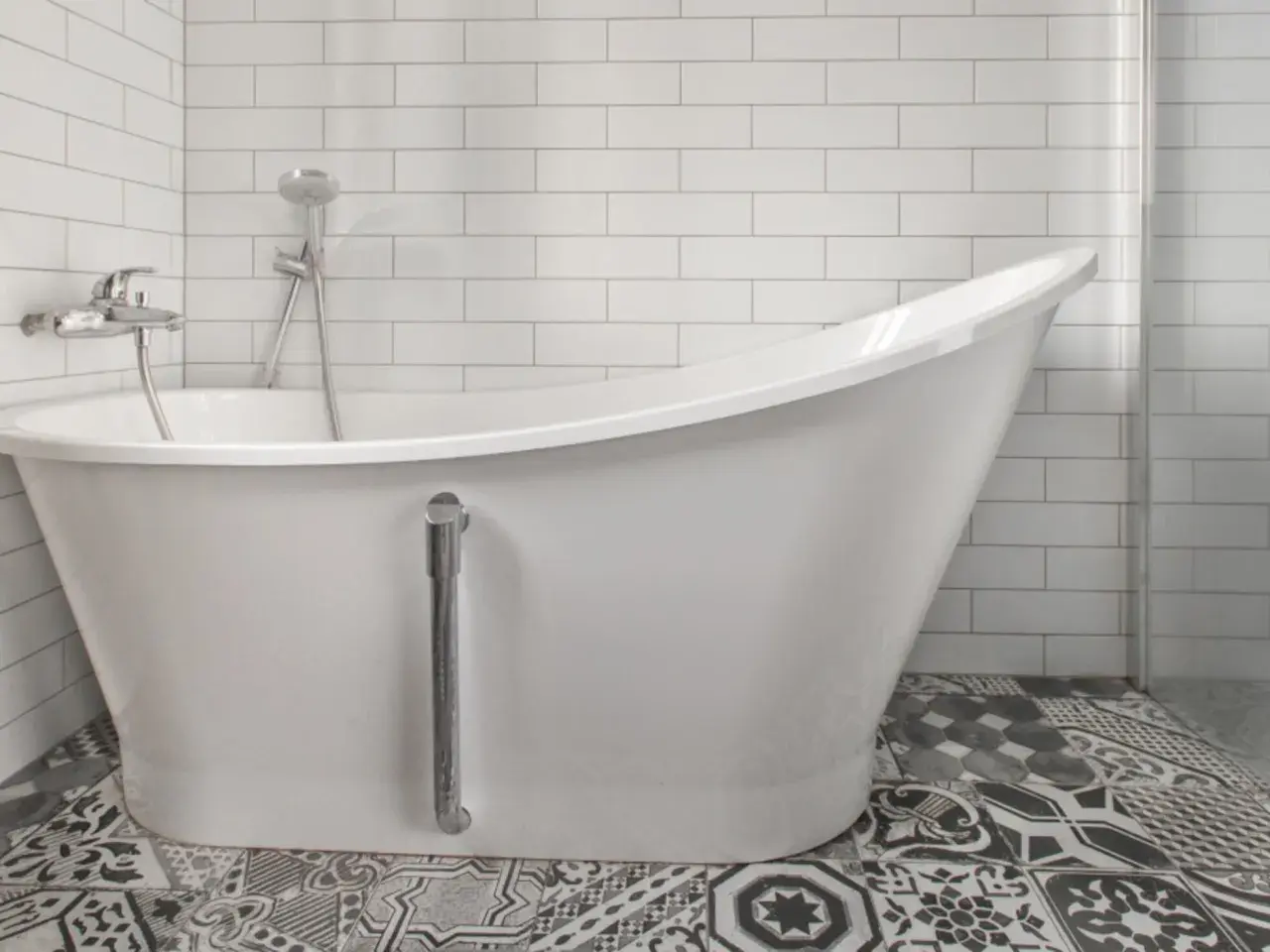 Baño moderno con bañera blanca y grifería cromada. El suelo tiene baldosas hidráulicas. Ideal para reparar bañera picada.