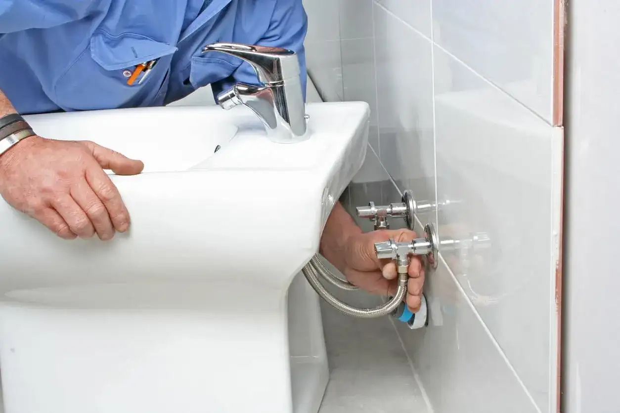 Fontanero desconectando mangueras de un bidet. Guía para como quitar un bidet paso a paso.