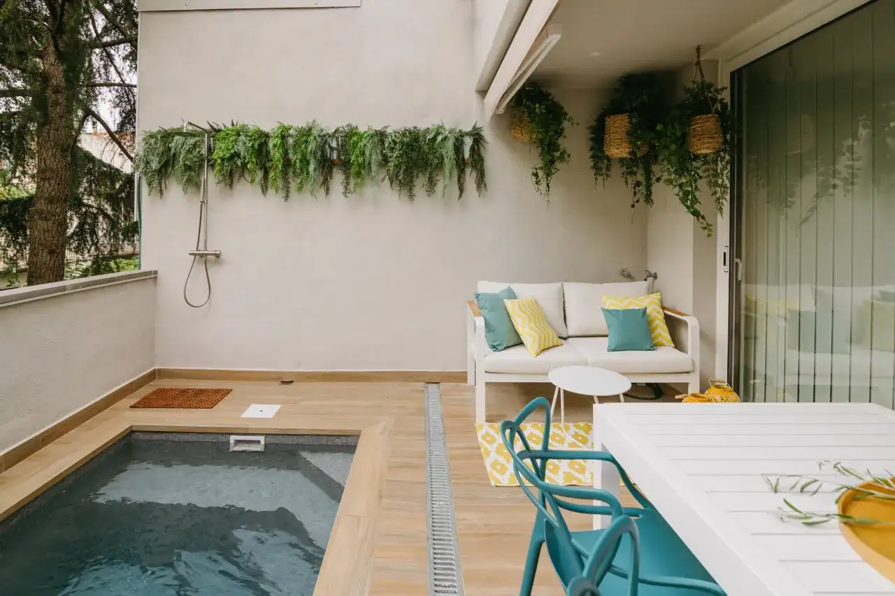 Un rincón acogedor con piscinas pequeñas con encanto, ducha exterior y zona de estar con sofá y mesa.