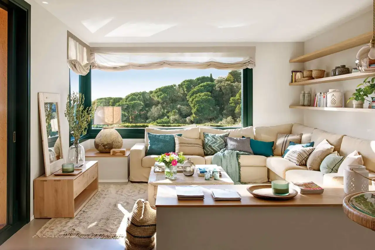 Salones modernos con sofá modular beige, mesa de centro de madera y gran ventanal con vistas al bosque.