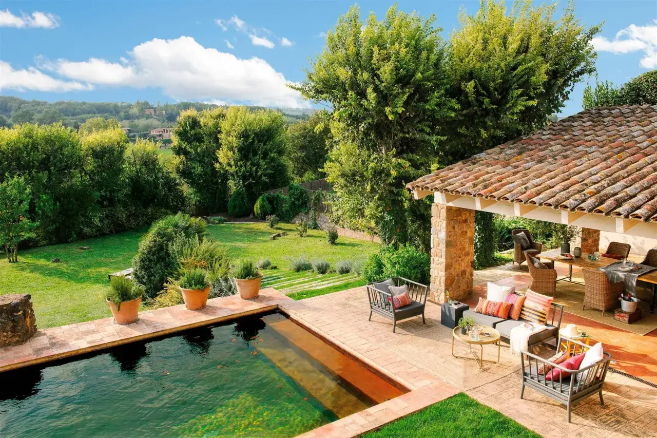 Un id&iacute;lico jard&iacute;n con piscina y un porche acogedor, perfecto para disfrutar del sol y la naturaleza.