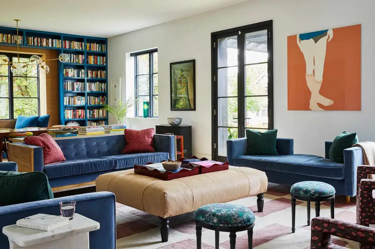 Sofá azul, alfombra a rayas, mesa de centro beige y estanterías llenas de libros. Ideas de colores para pintar un salón.