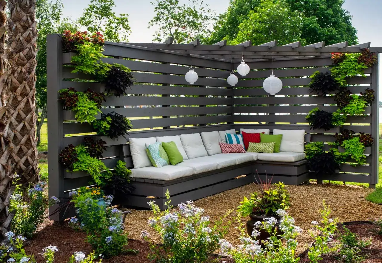 Rincón de patio con sofá modular y plantas colgantes. Una idea genial para decorar patio sin dinero, con cojines coloridos y farolillos.