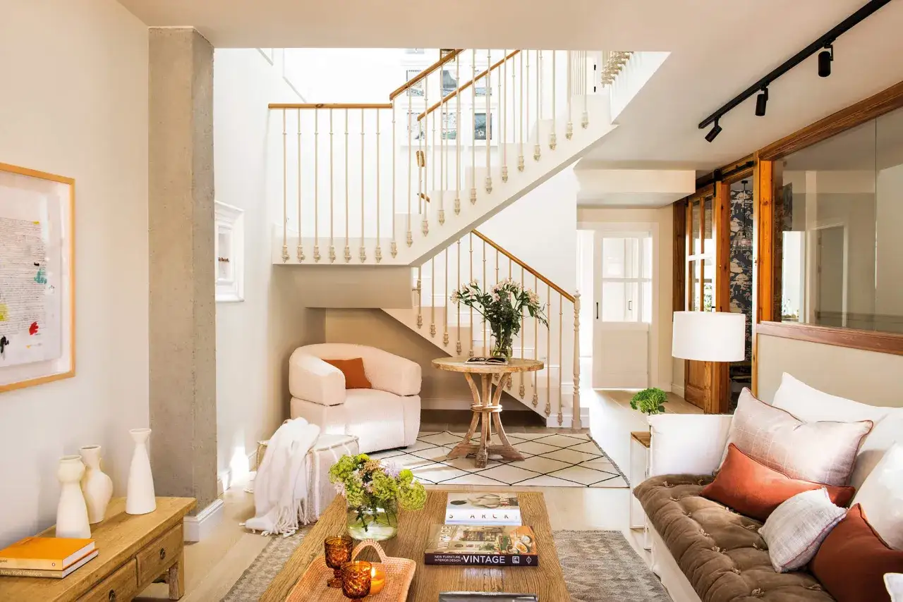 Un sal&oacute;n moderno con una escalera antigua que parece revestir el espacio con elegancia.