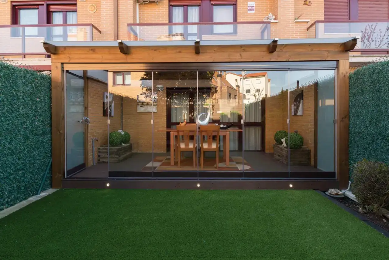 P&eacute;rgola de madera con cerramiento de cristal, ideal para cerrar tu espacio exterior.