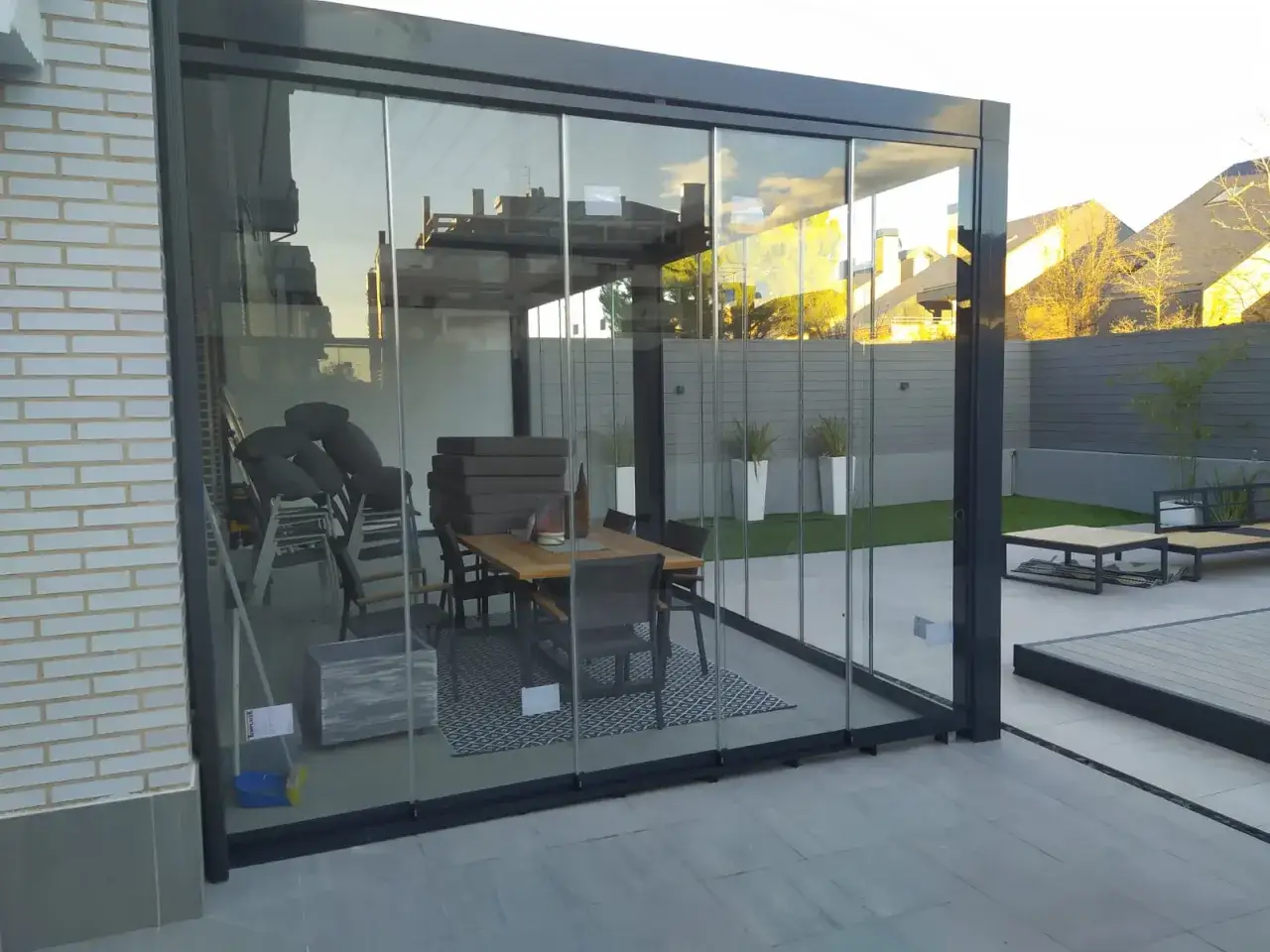 Terraza acristalada con mesa y sillas. Soluci&oacute;n para como tapar la vista del vecino en terraza, creando un espacio privado y acogedor.