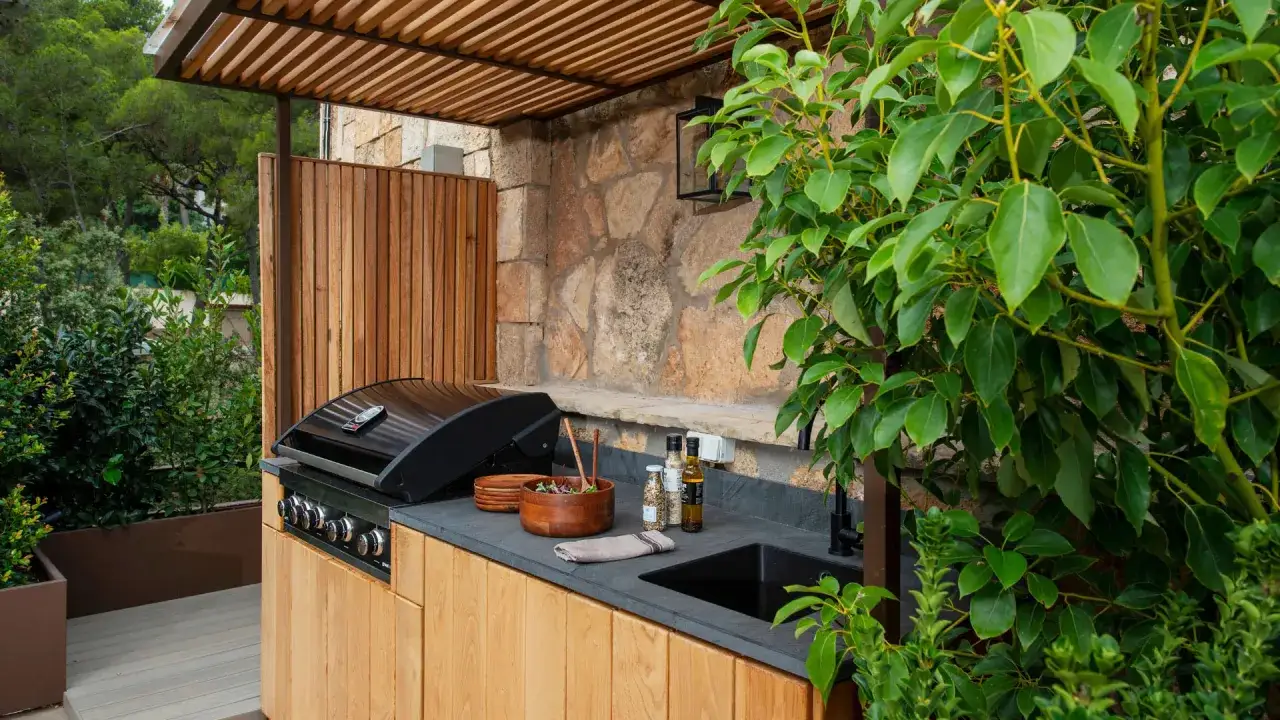 Cocina exterior moderna con parrilla, fregadero y encimera de piedra. Un rinc&oacute;n perfecto para disfrutar de quinchos modernos y reuniones al aire libre.