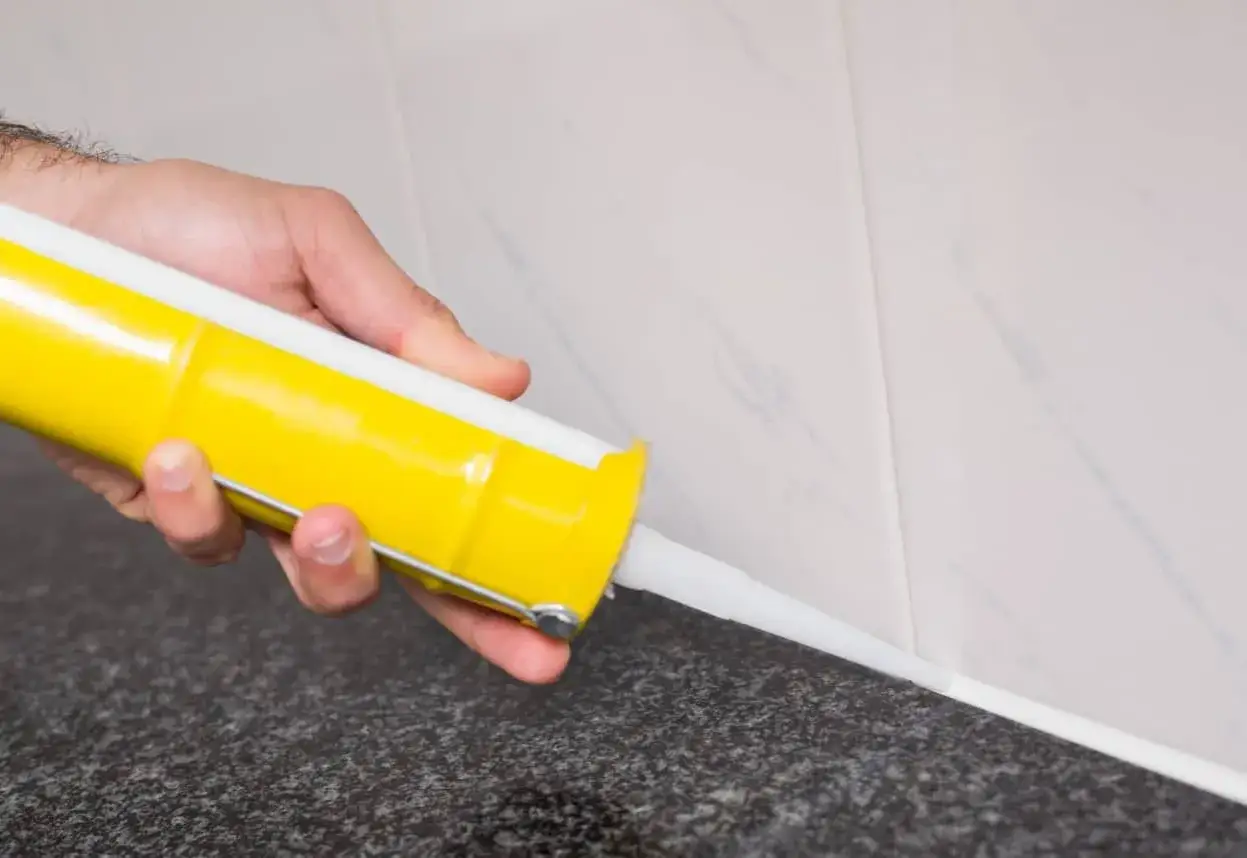 Mano aplicando silicona en juntas de azulejos. Gu&iacute;a visual de como aplicar silicona en juntas para un acabado perfecto.