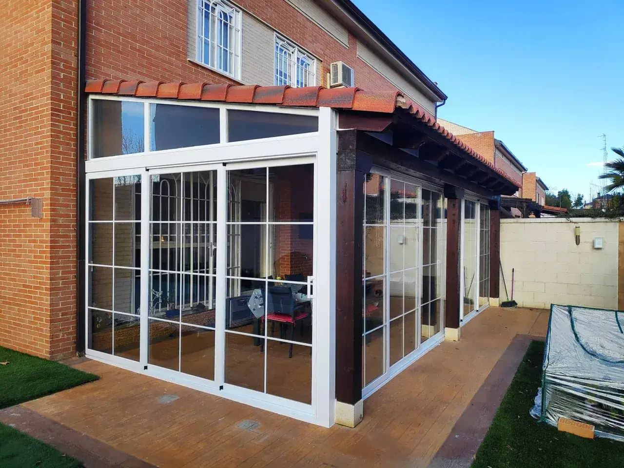 Moderno cerramiento de terraza con grandes ventanales blancos, creando un espacio luminoso y funcional.