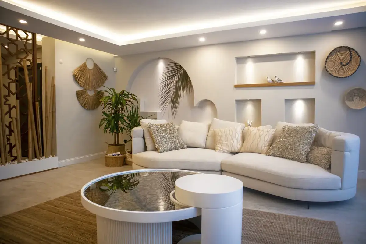 Un sal&oacute;n moderno y acogedor, ideal para aprender como iluminar un salon. Sof&aacute; curvo, mesa de centro redonda y decoraci&oacute;n natural.