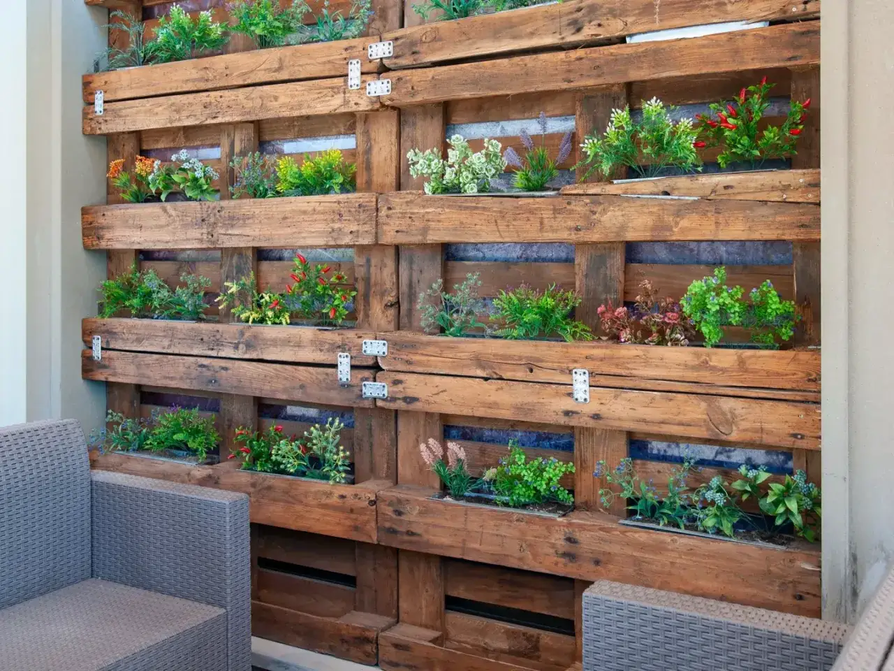 Un jardín vertical con palets crea un oasis verde. Plantas de colores vibrantes crecen en compartimentos de madera rústica, invitando a la relajación.