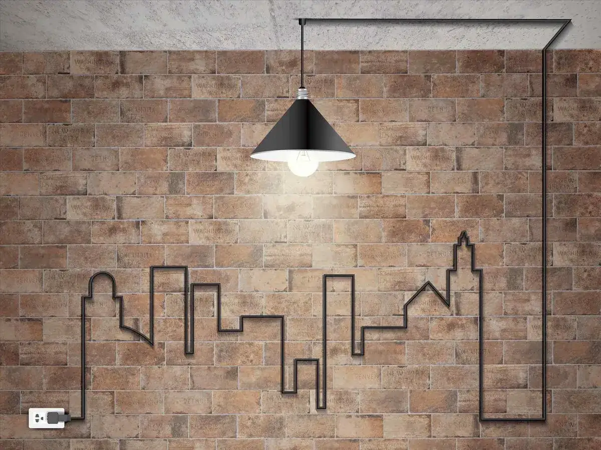 Creativas ideas para tapar cables en la pared formando un skyline urbano. Un enchufe alimenta la escena.