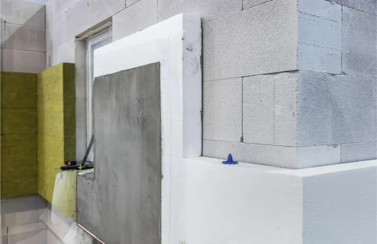 Detalle de aislamiento de fachada con lana de roca y poliestireno expandido, mostrando la mejora de la transmitancia t&eacute;rmica de los materiales.