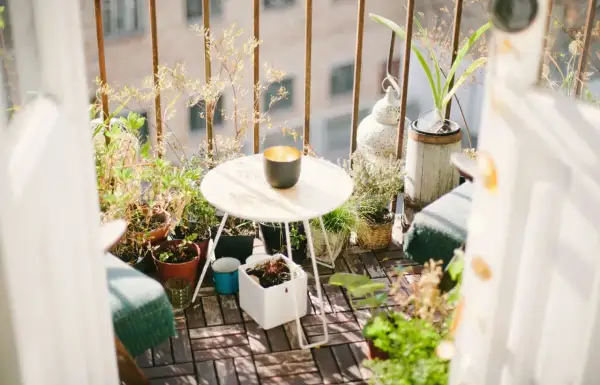 Ideas para aprovechar balcones pequeños: un rincón acogedor con plantas, mesa y silla, creando un oasis verde.