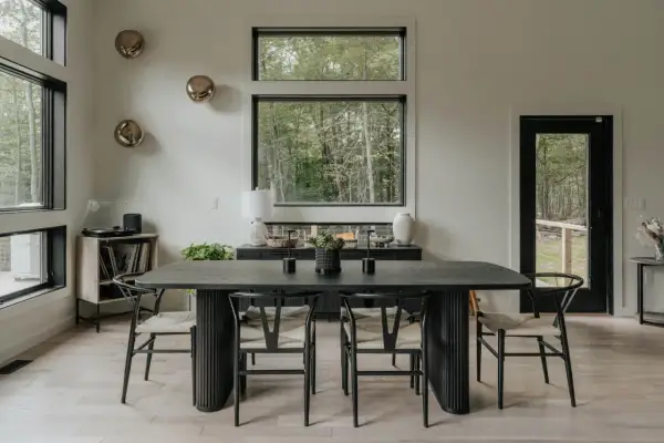 Mesa de comedor moderna con sillas de madera y asientos de mimbre. Un jarrón blanco y dos candelabros negros decoran la mesa, perfecta para decorar mesa comedor.