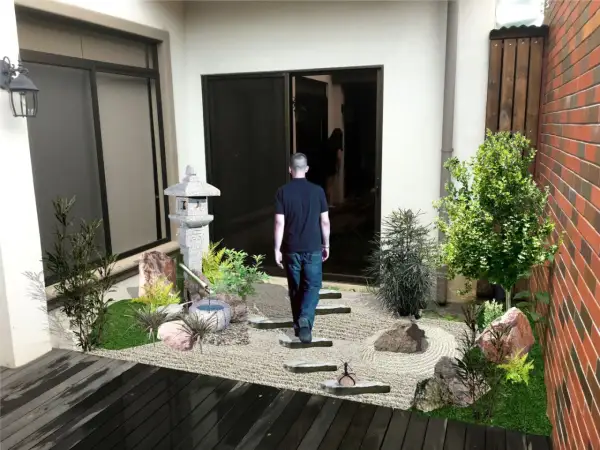 Un hombre camina hacia un sereno **patio jardín japonés en casa**, con una linterna de piedra y un estanque de bambú.