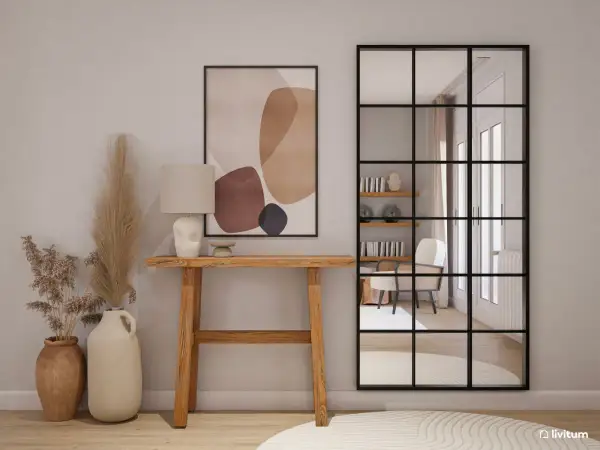 Entradas pequeñas con encanto: consola de madera, lámpara, cuadro abstracto y espejo industrial que refleja un sillón.
