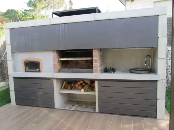 Cocina exterior con parrilla, horno de leña, bacha y anafe. Un ejemplo de quinchos modernos, ideal para disfrutar al aire libre.