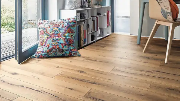 Suelo laminado de madera con un cojín colorido y estantería. Ideal para aprender como poner suelo laminado.