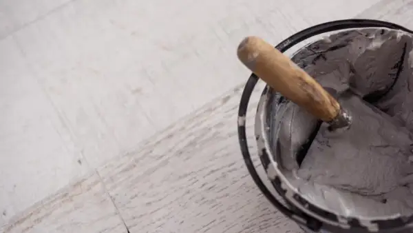 Paleta con morteros de revestimiento listos para aplicar sobre suelo de madera.
