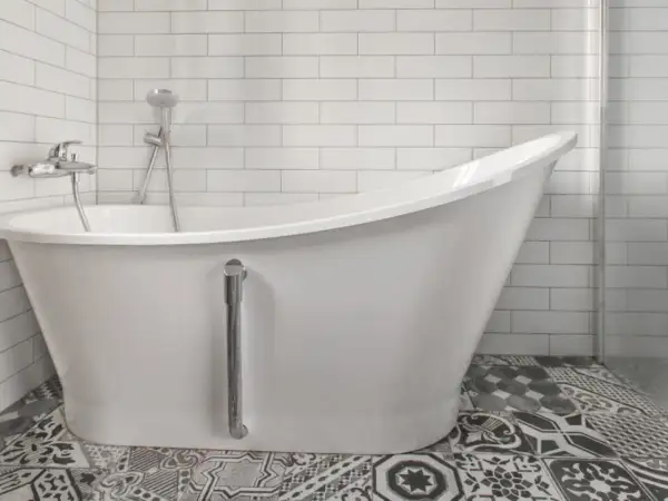 Baño moderno con bañera blanca y grifería cromada. El suelo tiene baldosas hidráulicas. Ideal para reparar bañera picada.